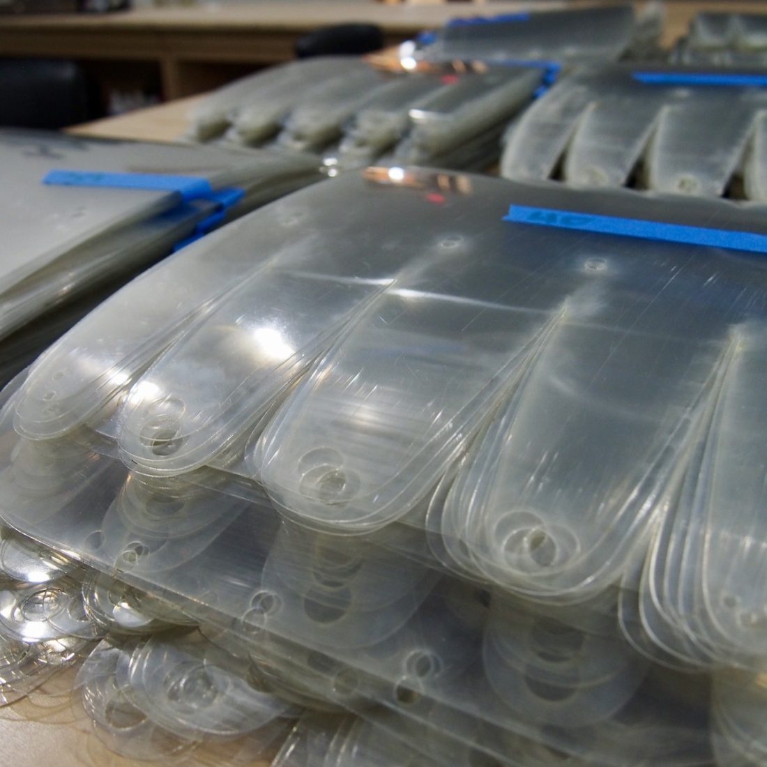 Piles of laser cut face shields waiting for assembly by our team.